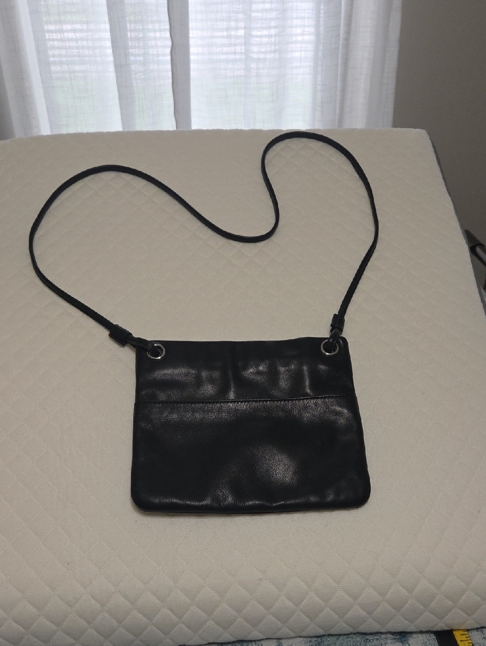 Sleek Black Leather Crossbody Bag with Grommet Detail